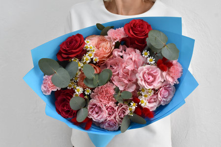 Woman with a bouquet of flowers. Beautiful flowers for the holiday. Woman with beautiful flowers in her hands indoors background. A bouquet of flowers for a flower shop.の写真素材