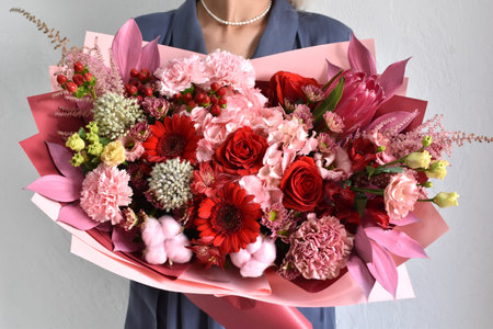 Woman with a bouquet of flowers. Beautiful flowers for the holiday. Woman with beautiful flowers in her hands indoors background. A bouquet of flowers for a flower shop.の写真素材