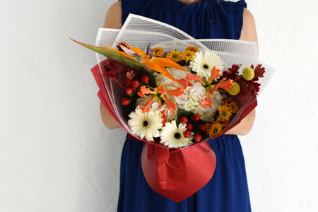Woman with a bouquet of flowers. Beautiful flowers for the holiday. Woman with beautiful flowers in her hands indoors background. A bouquet of flowers for a flower shop.の写真素材