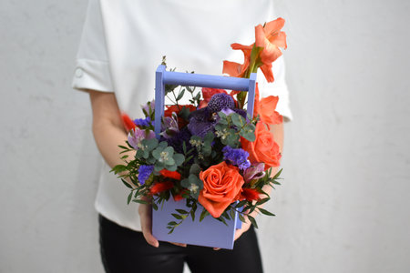 flowers in a hat box. woman with a bouquet of flowers. online catalog of flower delivery shop. plant bloom compositionの写真素材