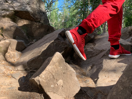 a man climbs uphill in the forest. mountain rock path. man climbs the hillの写真素材