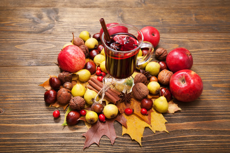 Mulled wine with spices and autumn decor on wooden tableの写真素材