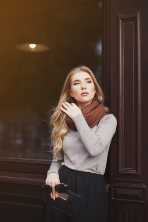 Street fashion concept: portrait of young beautiful lady posing at the window. Waist up. City lifestyle.の写真素材