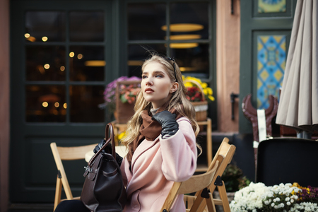 Portrait of beautiful stylish young woman sitting in street cafe . Model looking aside. City lifestyle. Female fashion.の写真素材