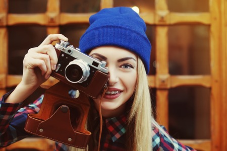Close up portrait of stylish happy smiling hipster girl in braces with vintage camera. Model looking at camera. City lifestyle. Toned.の写真素材