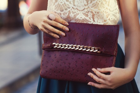Elegant outfit. Closeup of leather bag in hands of stylish woman. Fashionable girl on the street. Female fashion. City lifestyle. Tonedの写真素材