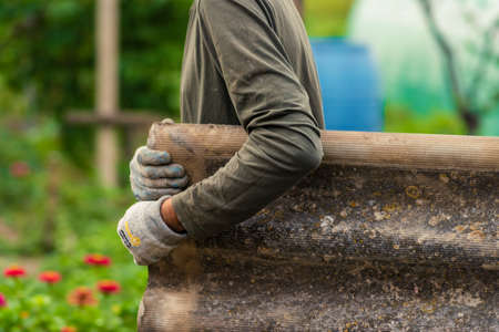 Risks nonProfessionals unprotected remove sheets of asbestos material from the roof of a rural home House with old, dangerの写真素材
