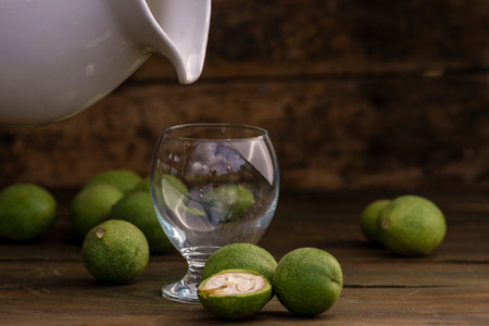 green walnut kernels leaves wooden table oil nuts unripe husks healthy food drink, old rustic table Background Harvest, organic Homemade plant based milk Dairy free jug glass cupの写真素材