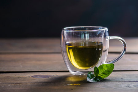 Herbal mint tea cup Transparent glass dark background wooden table still life honey bowl metal kettle teapot spoon cozyの写真素材