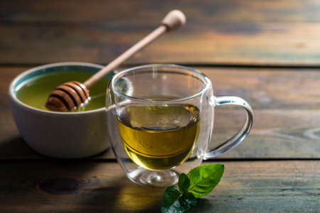 Herbal mint tea cup Transparent glass dark background wooden table still life honey bowl metal kettle teapot spoon cozyの写真素材