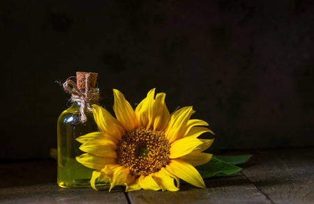 glass Bottle of sunflower oil with flower. wooden table. black background still life Natural Homemade rustic. beautiful.の写真素材