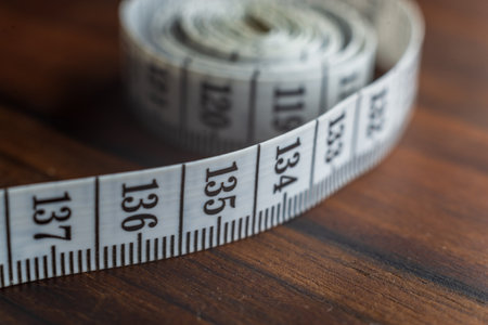 Close up tailor measuring tape on wooden table background. White measuring tape shallow depth of field.の写真素材