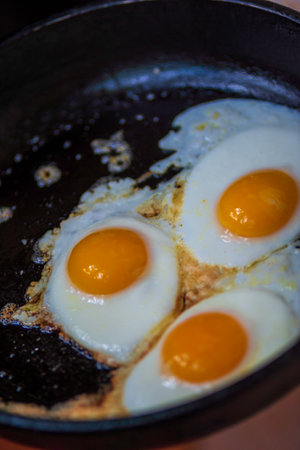 three eggs fried in frying pan scrambled eggs. Healthy food, nutritious delicious breakfast hot oilの写真素材