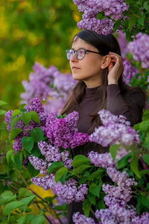 27 weeks Pregnant european with glasses woman tenderly hugs her belly surrounded by lilac flowers outside girl sunset Tummy new life concept brown drees springの写真素材