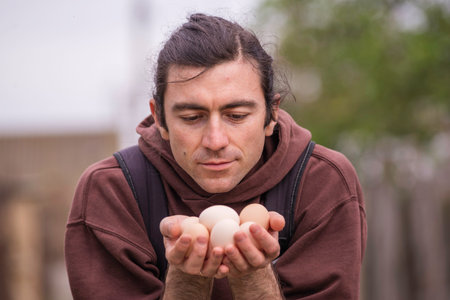 Happy young man Farmer portrait holding hands eggs fresh organic Chicken RawClose up ecologically grown hens in barn of countryside agricultural farm bio and eco farming, bio food products .の写真素材
