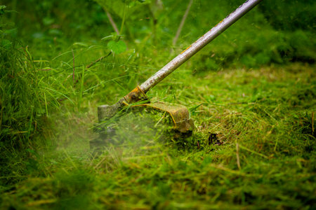 Caucasian Gardener working man Manual hand grass cutter Weed Cutter or Power Weeder or Brush Cutter Lawn Mowe Gasoline close upの写真素材
