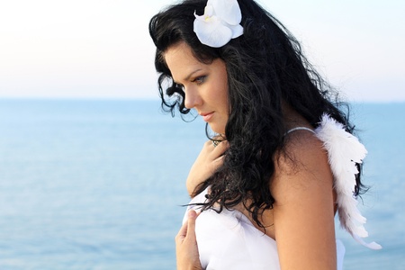 Portrait angel woman wearing angelic wings over white, outdoorsの写真素材