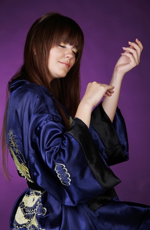 Back of woman in Oriental robe over dark purple, play handsの写真素材