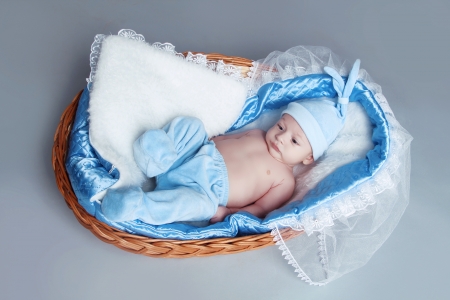 Adorable baby boy wearing in blue clothes resting in basketの写真素材
