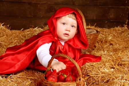 Lovely girl is sitting on pile of straw with a basketの写真素材