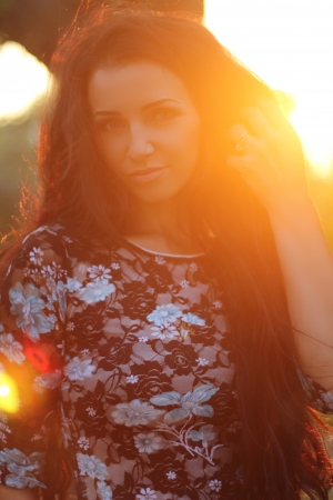 Enjoyment, free happy woman enjoying sunset. Beautiful brunette girl model embracing the golden sunshine glow of sunset with arms outspread and face raised in sky enjoying peace. Outdoors Portraitの写真素材