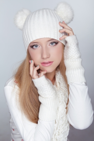 Beautiful teen girl wearing winter clothing and funny white hat. Isolated on grey backgroundの写真素材