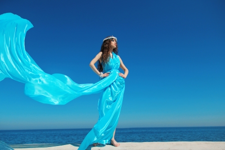 Fashion model woman with blowing dress over blue sky, outdoorsの写真素材