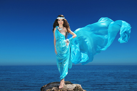 Fashion happy model woman with blowing dress over blue sky, outdoorsの写真素材