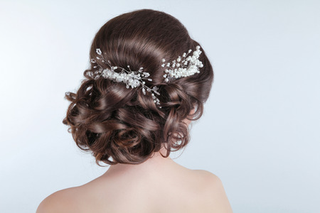 Beauty wedding hairstyle. Bride. Brunette girl with curly hair styling with barrette.