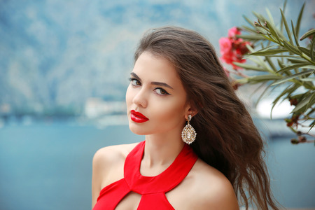 Beautiful girl with red lips, long wavy hair and fashion earrings.の写真素材