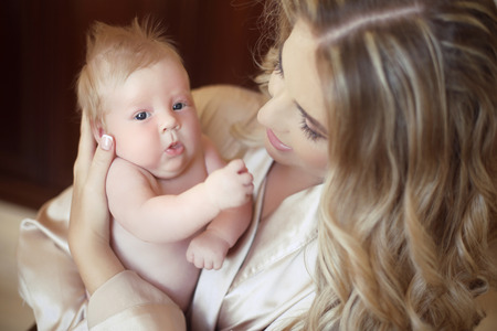 Beautiful mother with baby. Mom hugging her daughter child. Happy Family concept. Home indoor portrait.の写真素材