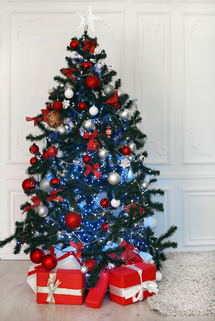 Christmas tree with red gifts decoration before white wall in holiday room interior home.の写真素材