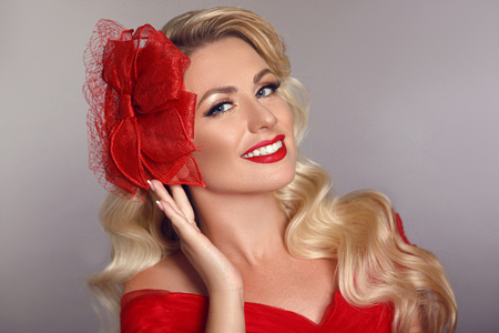 Beautiful elegant woman with red lips in fashion hat laughing over gray studio background. Attractive blonde model with happy face and teeth whitening. Pretty blond portrait.の写真素材