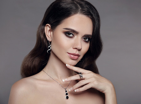 High Fashion brunette model woman in diamond  jewelry set isolated on gray background. Beauty female face, beautiful make-up.の写真素材