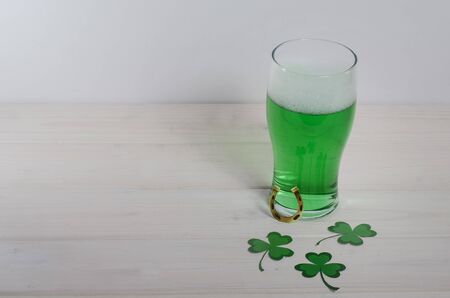 Holiday St. Patrick's Day. Green beer with clover and horseshoe on a white wooden background with...