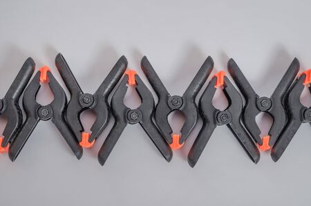 Black and orange construction clamps on a white background. Set of medium plastic clips. Clamping...
