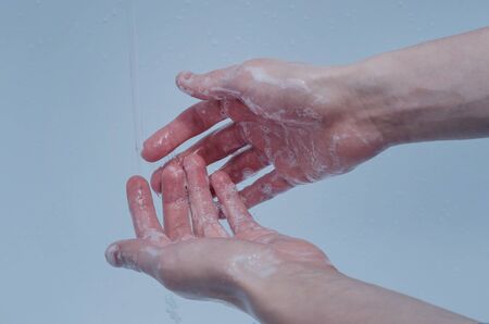 A young man washes his hands with soap in the bathroom. The concept of preventing the spread of the virus during an epidemic. Quarantine due to coronavirus.の写真素材