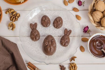 Home made chocolate easter eggs in the shape of a rabbit and chicken on a wooden white background...