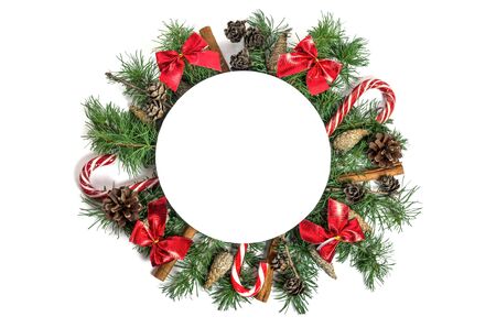 Christmas and New Year composition in the form of a circle with copy space. Coniferous branches, pine cones, sweets and bows isolated on white background. Flat lay. View from aboveの写真素材