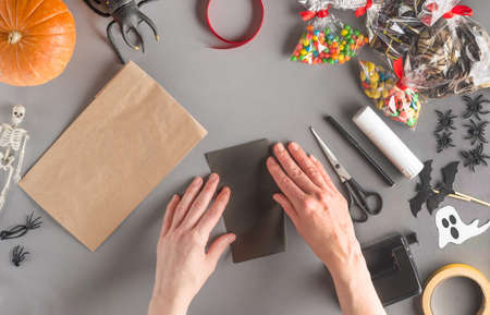 Step-by-step wrapping of a gift for Halloween, flat lay. Step 4 - take black paper and fold it in halfの写真素材