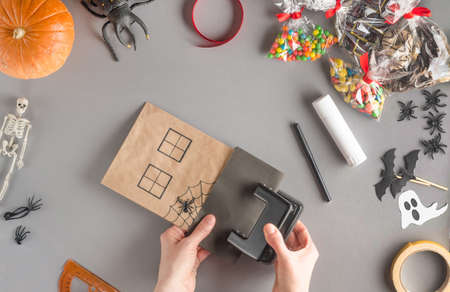 Step-by-step wrapping of a gift for Halloween. Step 14 - make holes on the roof of the house with a hole punchの写真素材