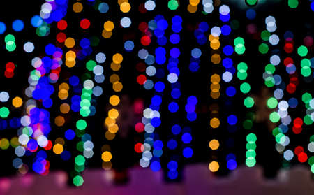 Festive blurred background of glowing garlands on the streets of the city for Christmas and New Year. Night walksの写真素材