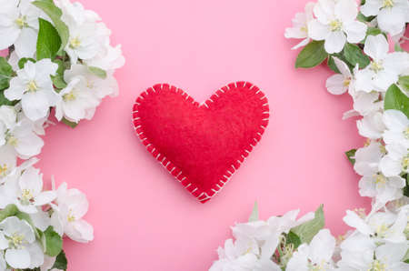 Valentines day card, red heart with a frame of flowers and leaves on a pink background