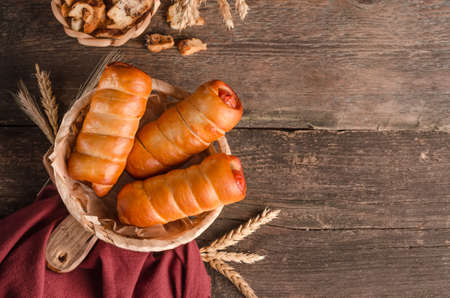 Delicious fresh culinary baked goods - sausages in dough with copy space on wooden background