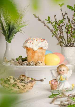 Easter cake and colorful eggs on a festive easter table with pussy willow and angel figurine