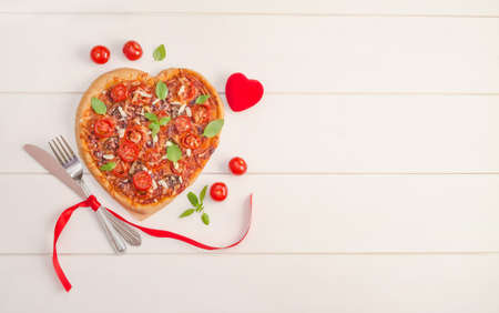 Valentine's day background with pizza heart on white wooden background with copy space.の写真素材