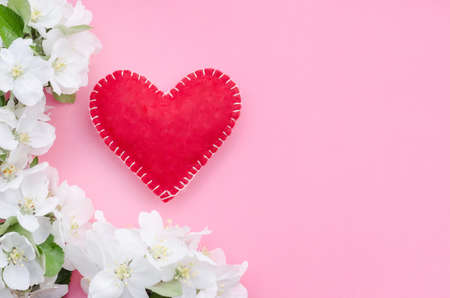 Valentines day card, red heart with a frame of flowers and leaves on a pink background with copy spaceの写真素材