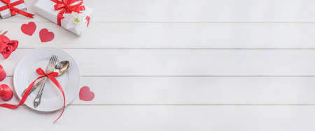 Banner with cutlery plate with hearts and gifts, Valentines Day romantic dinner concept on white wooden background with copy spaceの写真素材