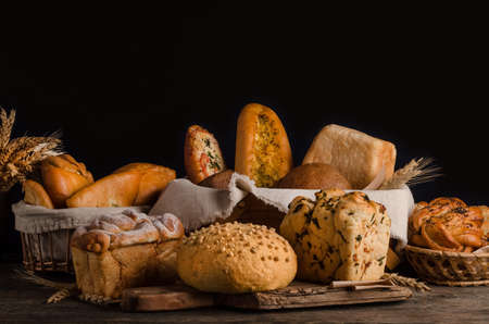 Still life of a varied assortment of breads on a black background, bakery banner