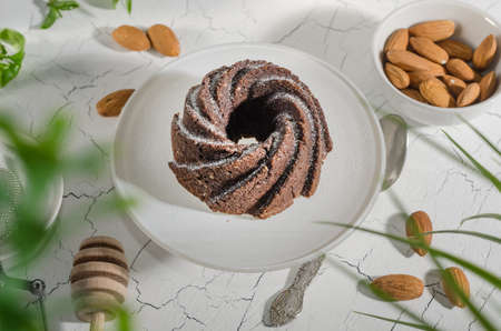 Chocolate brownie with almonds and powdered sugar on a white stand with hard light with selective...